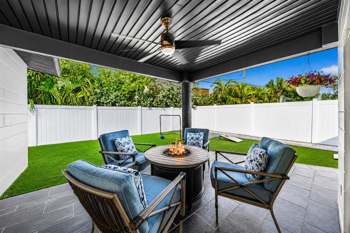 Spacious backyard patio with fire table, outdoor seating, and private fenced yard.
