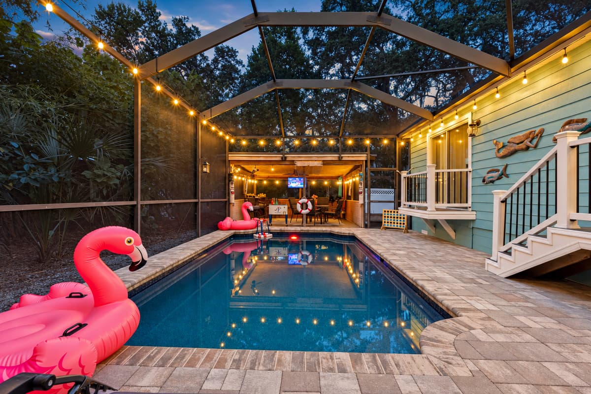 This inviting pool space offers both relaxation and entertainment, complete with lounge chairs, floats, and a cozy adjacent patio bar.