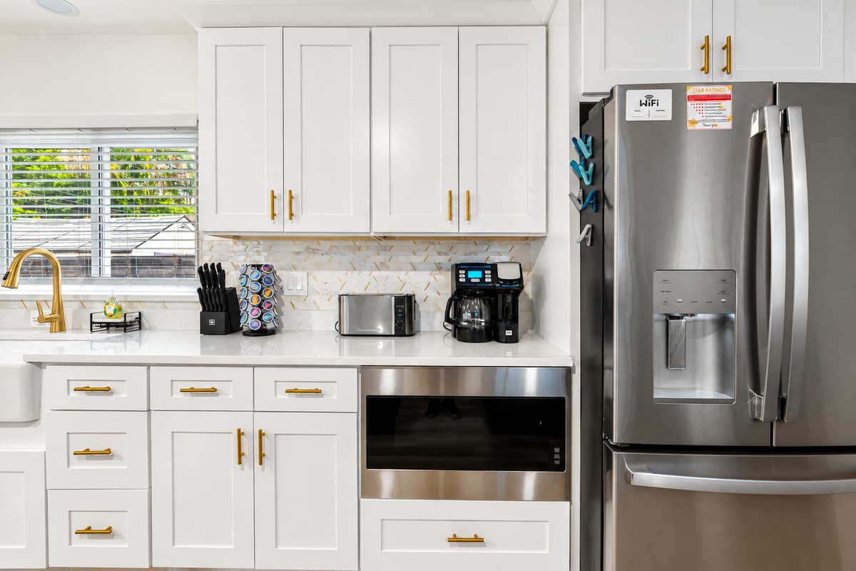 Crisp white cabinets, gold hardware, and quartz counters give this kitchen timeless elegance.