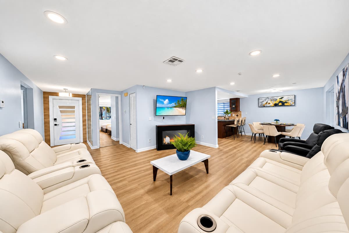 Spacious open-concept living room featuring comfortable reclining sofas, a large TV, and plenty of seating for family gatherings and movie nights.