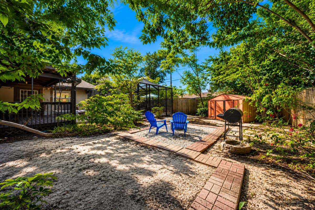 Spacious backyard retreat featuring shaded outdoor seating, a grill area, and relaxing natural landscaping.
