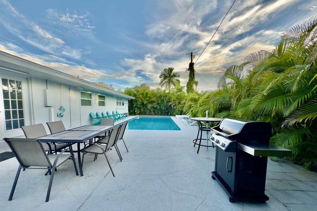 The backyard combines comfort and function, with sun loungers, dining space, and a modern barbecue.