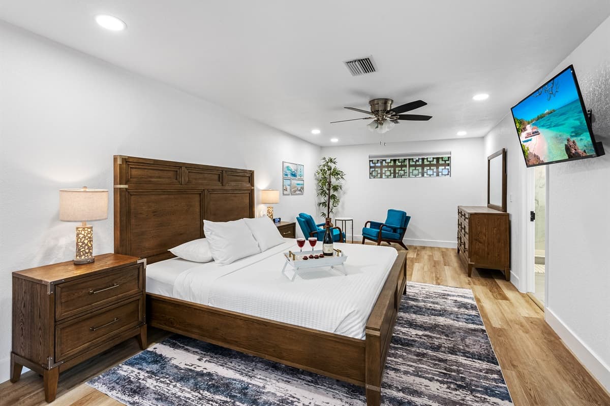Relax in this airy, light-filled bedroom with upscale furniture, a mounted flat-screen TV, and a private sitting area ideal for wine or winding down.