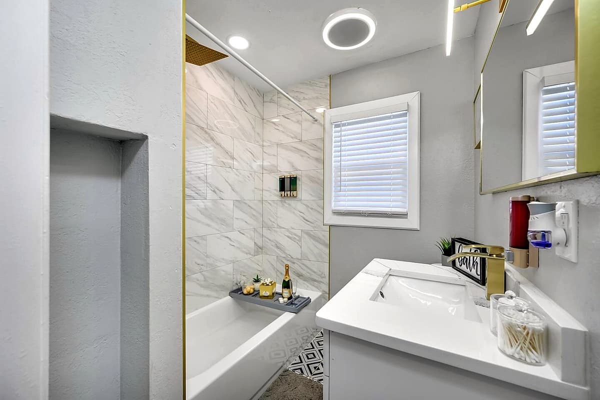 This bathroom has a bathtub, sink, toilet, shower, and wide vanity mirror.