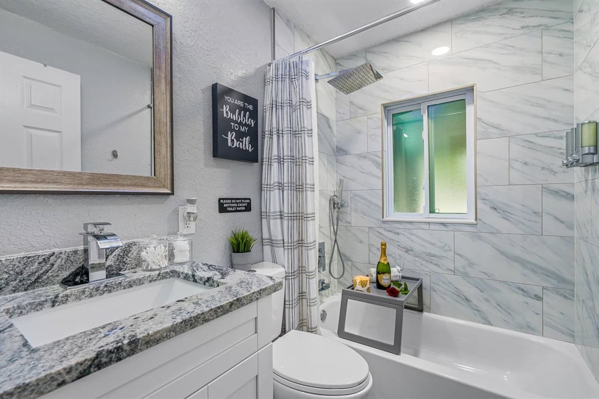 This bathroom has a bathtub, Sink, toilet, shower, and wide vanity mirror.