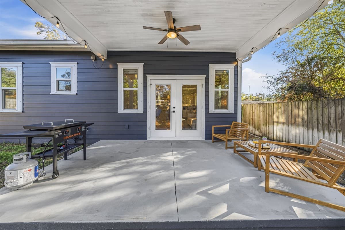 Entertain or unwind on the spacious covered back patio — complete with ceiling fan, picnic-style dining table, wooden lounge seating, and direct French door access. Your private outdoor oasis in brand-new Seminole Heights.