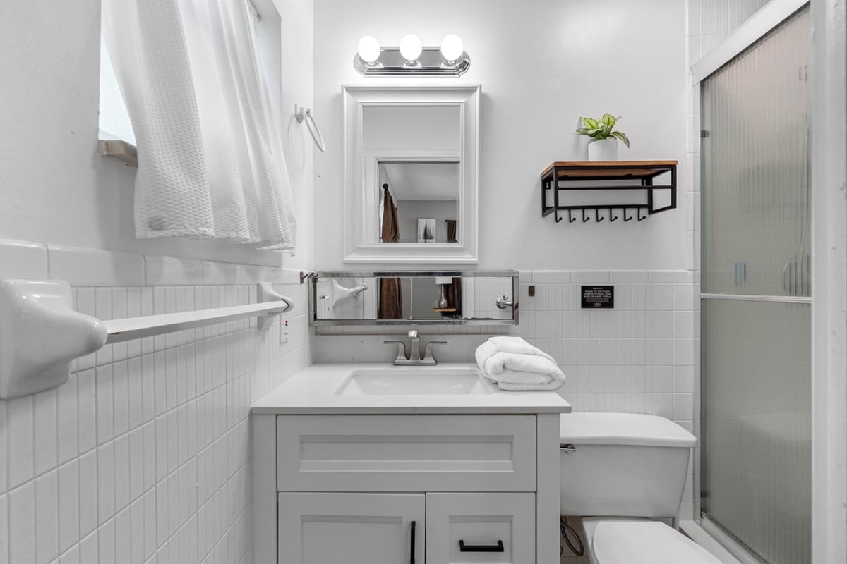 This bathroom features crisp white finishes, a sleek vanity, and bright lighting, creating a fresh and modern feel.