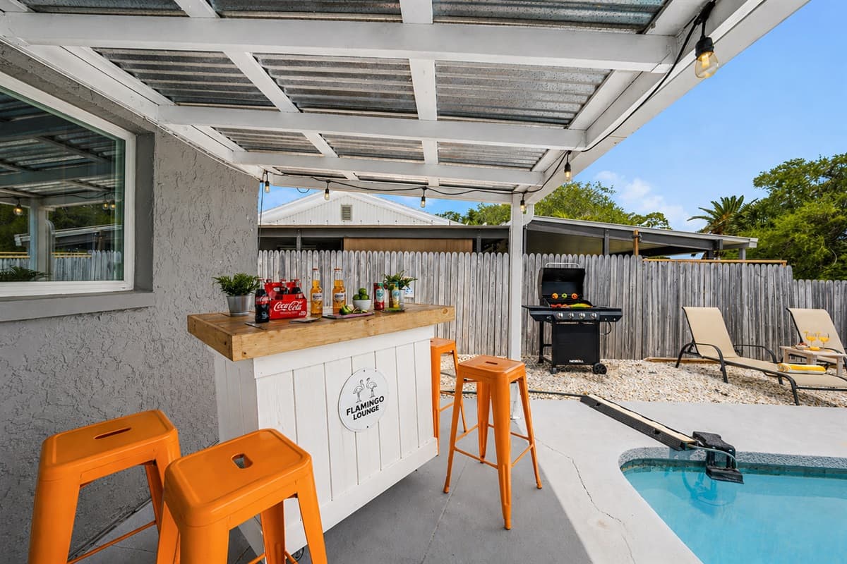 Covered patio with outdoor bar seating overlooking the pool—perfect for relaxing and entertaining.