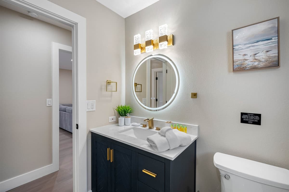 A chic retreat featuring a gleaming gold faucet set, marble-top vanity, and rainfall shower — the perfect setting to start or end your day in style.