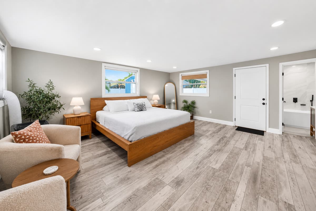Spacious primary bedroom with a king-size bed, comfortable sitting area, en-suite bathroom access, and abundant natural light.