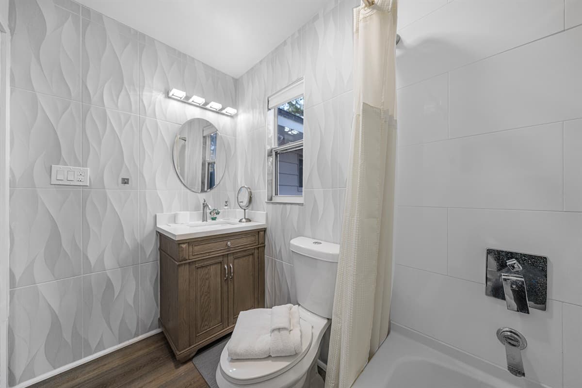 The bathroom offers a clean and refreshing space, complete with modern tile accents and a well-appointed vanity.