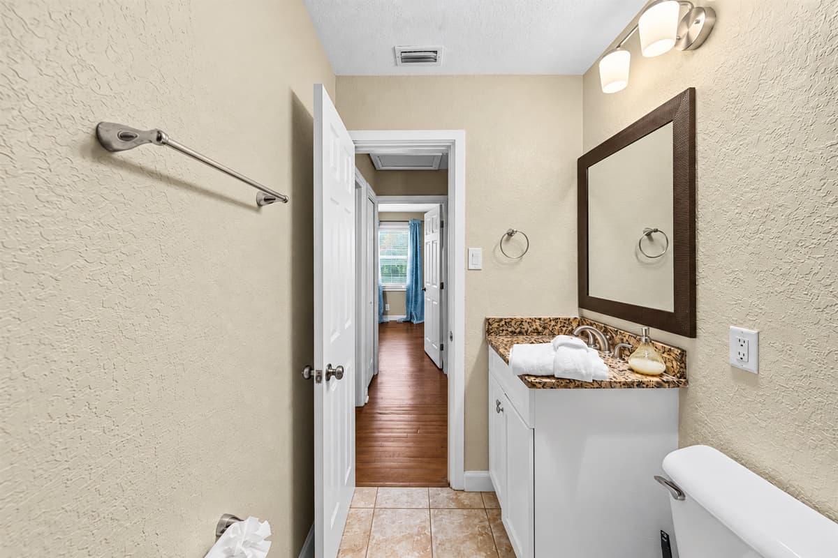 Bathroom vanity area with mirror and storage, conveniently located near bedrooms.
