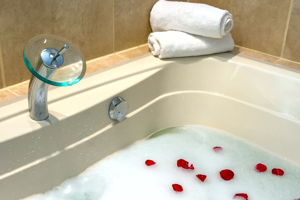 The ensuite bathroom features a double vanity, soaking tub, and warm tile accents.