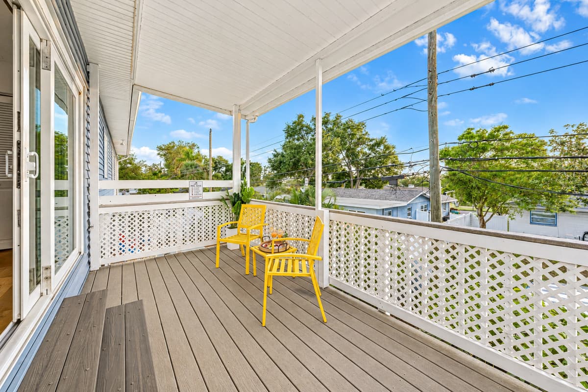 Spacious covered balcony with bright yellow seating—perfect for relaxing outdoors 
