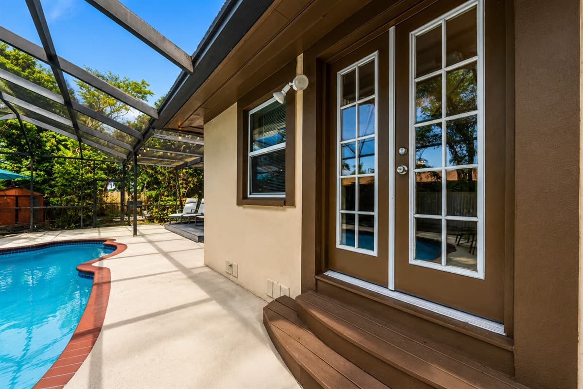 Cozy poolside entrance featuring French doors and a peaceful screened enclosure.