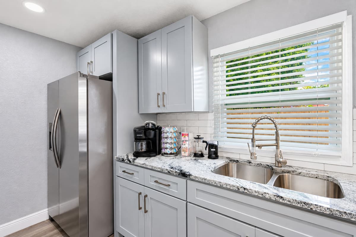 Stainless, granite, and room to cook. A full-size stainless fridge, double sink, and granite counters under a sunny window. Prep fresh seafood or a family breakfast with plenty of space for helpers.