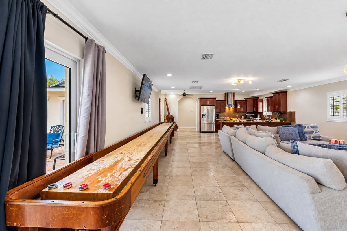 This game space features a vintage shuffleboard table and mounted TV, ideal for casual entertainment.