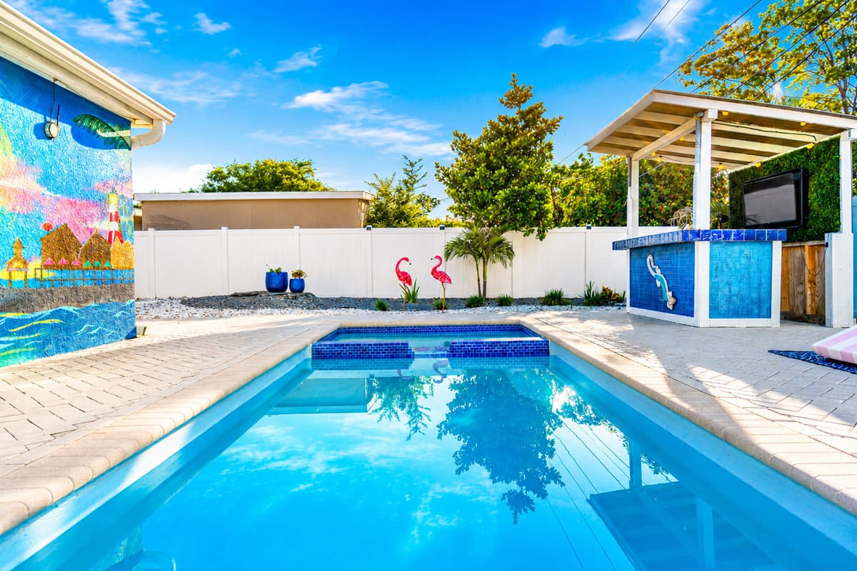 Sparkling private pool with an integrated spa, surrounded by colorful coastal murals and a resort-style backyard setting.