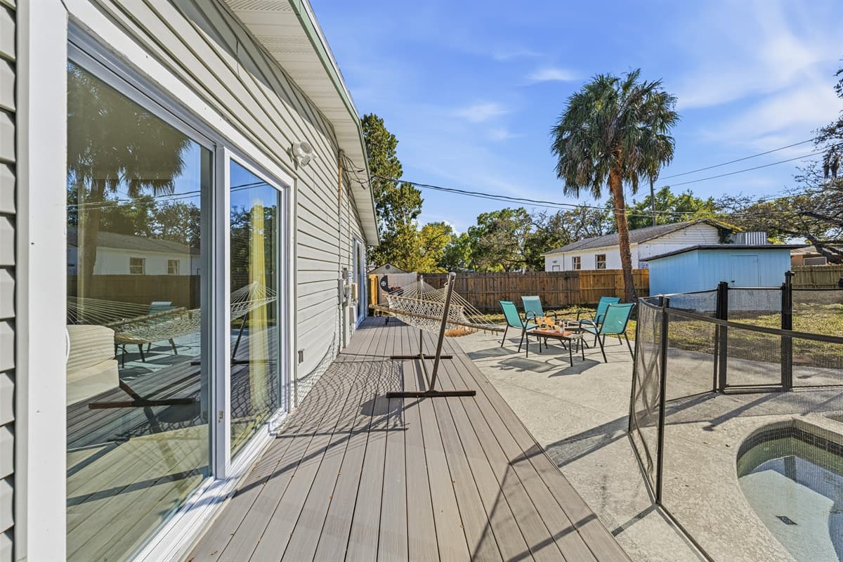Spacious wooden deck with sliding glass doors and pool access.