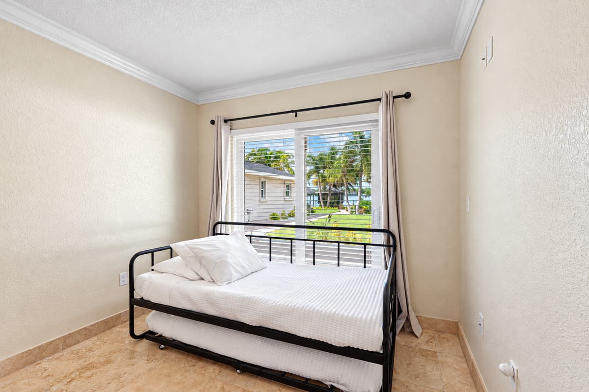 This cozy room features a daybed with trundle, perfect for flexible sleeping arrangements, and a large window with views of the yard and water beyond.