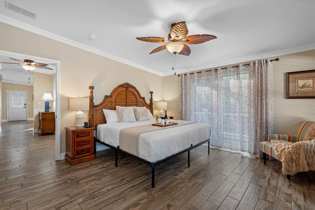 This serene master suite offers a spacious retreat with elegant coastal décor and warm natural light flowing through the large windows.