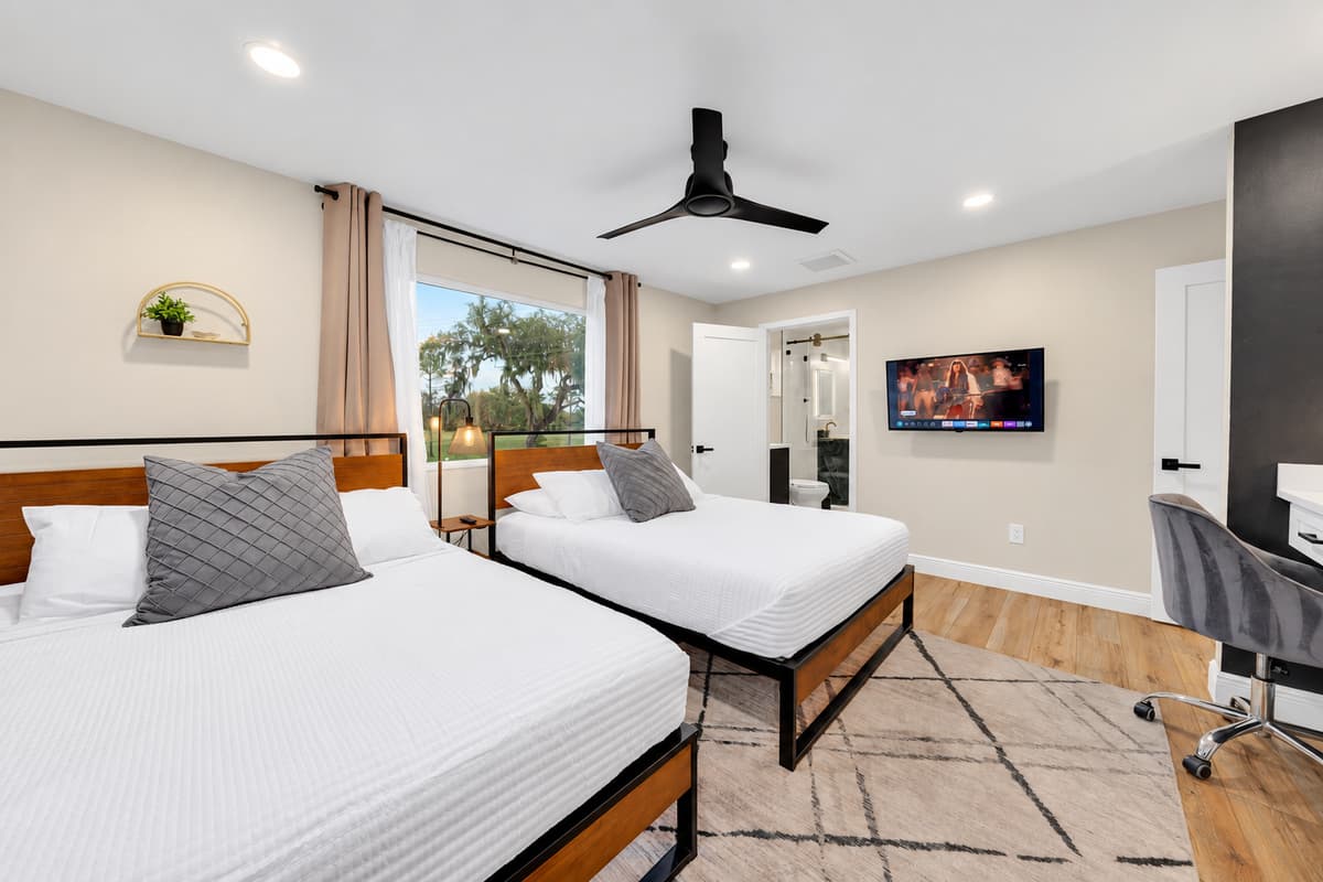 Two queens, a desk and a screen of your own. Bright, vaulted ceiling, fan on low and room for four to share comfortably — the flexible bedroom that adapts to whoever ends up in it.