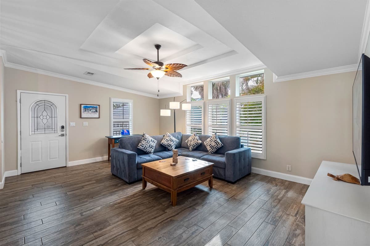 Relax in this beautifully designed living room, where large windows, soft tones, and a roomy sectional create the perfect spot to unwind after a day at the beach.